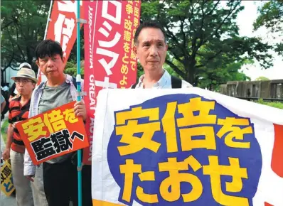  ?? MA PING / XINHUA ?? Protesters hold banners and shout slogans against Prime Minister Shinzo Abe in Hiroshima, Japan, on Sunday.