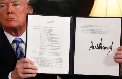  ?? (Reuters) ?? US PRESIDENT Donald Trump holds up a proclamati­on declaring his intention to withdraw from the JCPOA Iran nuclear agreement in May.