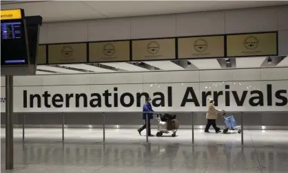  ?? Photograph: Matt Dunham/AP ?? Arriving passengers walk past a sign in the arrivals area at Heathrow Airport in London, during England’s third national lockdown.