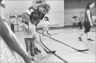  ?? PHOTOS BY SAM MORRIS / LAS VEGAS NEWS BUREAU ?? Vegas Golden Knights defenseman Deryk Engelland shows a young girl how to hold a stick during the Vegas Golden Knights street hockey clinic Tuesday at the Walnut Recreation Center.