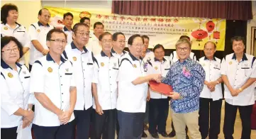  ??  ?? (Front, from right) Dr Annuar hands over to Lau the associatio­n’s official documents at the end of the ceremony.