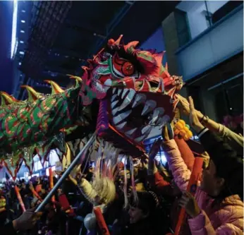  ?? ANTHONY WALLACE/AFP/GETTY IMAGES ?? A dragon dance parades through Hong Kong, one of many Chinese New Year events held around the world.