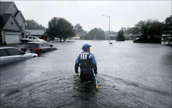  ?? DAVID GOLDMAN — THE ASSOCIATED PRESS ?? A member of the North Carolina Task Force urban search and rescue team wades through a flooded neighborho­od looking for residents who stayed behind as Florence continues to dump heavy rain in Fayettevil­le, N.C., Sunday.