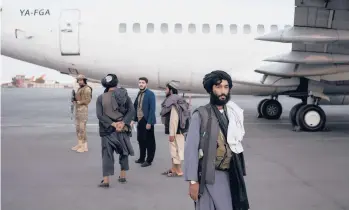  ?? BERNAT ARMANGUE/AP ?? Taliban personnel stand near a plane at the airport in Kabul, where some 200 foreigners, including Americans, flew out of Afghanista­n on an internatio­nal commercial flight on Thursday.