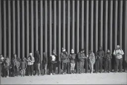  ?? REBECCA NOBLE/AFP VIA GETTY IMAGES ?? Asylum-seekers line up to be processed by U.S. Customs and Border Patrol agents at the U.S.Mexico border fence near Somerton, Ariz. on Dec. 26, 2022.