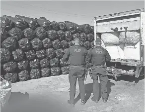  ??  ?? Officers inspect plastic bags filled with recycled bottles and cans in an Arizona trucking yard.