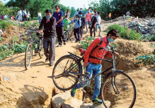  ?? PTI ?? FACTORY workers walk through a forested area in an attempt to cross the Delhi-gurgaon border after they were stopped by the Haryana Police following the sealing of the border after a surge in coronaviru­s cases, on June 1.