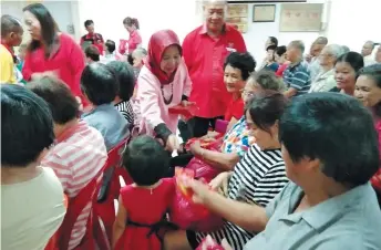  ??  ?? Rosey presents angpows to senior citizens. Behind her is Penghulu Haw Min Wai.