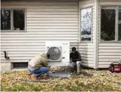  ?? NYT ?? Nick Bender (right) and Thorsten Busch install a new heat pump at a home in Shorewood, Minn., on Nov. 1. President Biden’s signature climate law offers tax credits of up to $2,000 per year for the purchase of heat pumps.