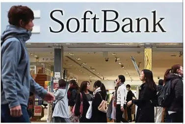  ?? — AFP ?? Higher earnings: A file picture showing people walking in front of a shop of SoftBank in Tokyo. SoftBank Group said its operating profit in the October-December quarter was 438.3 billion yen (US$3.99bil) versus 274 billion yen a year earlier.