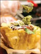  ??  ?? Michael Thompson, an employee at Salsarita’s, puts guacamole on a customer’s taco salad.