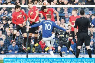  ?? — AFP ?? MANCHESTER: Manchester United’s English defender Harry Maguire (C) defends a free-kick from Everton’s Icelandic midfielder Gylfi Sigurdsson during the English Premier League football match between Everton and Manchester United at Goodison Park in Manchester United, north west England yesterday.