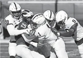  ?? RICK OSENTOSKI/USA TODAY SPORTS ?? Michigan running back Hassan Haskins is tackled by Penn State defenders Jayson Oweh (28) and Jaquan Brisker (1) on Saturday.