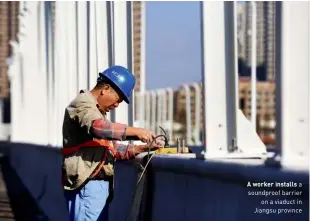  ??  ?? A worker installs a soundproof barrier on a viaduct in Jiangsu province