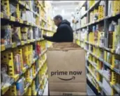  ?? MARK LENNIHAN — THE ASSOCIATED PRESS FILE ?? A clerk reaches to a shelf to pick an item for a customer order at the Amazon Prime warehouse in New York.