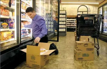  ??  ?? Tom Boyle, the Overnight Senior Team Leader at the South Hills Market District, loads a cooler during his shift. He arrives for work by 10:30 p.m. and must make certain the store is prepared for a new day of business by 7:30 a.m. the following day.