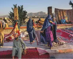  ?? AP ?? Afghan women walk through a second-hand market in Kabul. Many families have sold their belongings before fleeing.