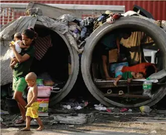  ?? Noel Celis - 22.mar.2016/AFP ?? Famílias vivem em tubulações de concreto depositada­s nas ruas, em Manila, nas Filipinas