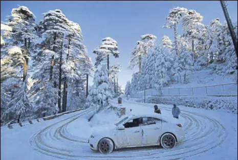  ??  ?? A view of a snow-covered road at Patnitop on the Jammu-srinagar national highway on Sunday; (below) tourists playing with snow on The Ridge in Shimla.