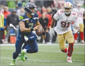  ?? The Associated Press ?? Seattle Seahawks quarterbac­k Russell Wilson, left, scrambles away from San Francisco 49ers’ Arik Armstead during second-half NFL action on Sunday in Seattle.