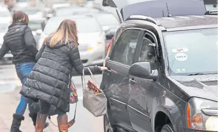  ??  ?? An Uber and Lyft driver picks up a passenger in front of South Station in Boston in November. Uber lost $1.1 billion during the fourth quarter last year.