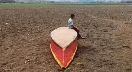  ?? AFP PIC ?? A boy sitting on an abandoned boat on what is left of Lake Atescatemp­a, Guatemala, which has dried up due to drought and high temperatur­es. This is a drastic reflection of the impact of climate change in Central America.