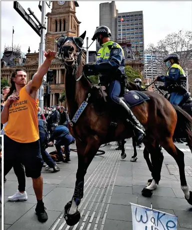  ?? AFP / GETTY ?? CLASHES: A police horse is attacked in Sydney, above. Protesters make their point with homemade placards, left and right