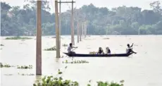  ?? — AFP ?? Villagers travel on a boat in the flood affected Morigoan district of Assam on Tuesday.