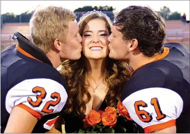  ?? Photo by Randy Moll ?? Bret Callahan and Cody Sullins give a ceremonial kiss to Alex Krewson after she was crowned homecoming queen at Gravette High School homecoming ceremonies in Lion Stadium on Oct. 21.