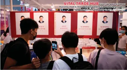  ?? AFP PHOTO ?? VITAL TRADE HUB
Visitors take photos of a banner illustrati­ng a book by Chinese President Xi Jinping at a booth at the annual Hong Kong Book Fair in Hong Kong on July 17, 2021.