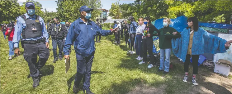  ?? ERNEST DOROSZUK / POSTMEDIA NEWS FILES ?? A city employee, backed by police, tells people to leave the homeless encampment area at Trinity Bellwoods Park in Toronto on June 22.