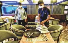  ?? ANI ?? ■
Workers arrange a table as the Delhi government announced the reopening of restaurant­s in the Indian capital from today.