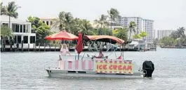  ?? AMY BETH BENNETT/SOUTH FLORIDA SUN SENTINEL ?? Ice Cream Float owner Amy McGill and her husband, Greg, drive her floating ice cream store up the Intracoast­al Waterway in Lighthouse Point on Thursday.