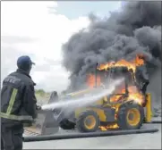  ??  ?? ABLAZE: A fireman douses a burning bulldozer set alight by protesters at a wine stall in De Doorns.