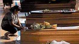  ?? GREGORIO BORGIA/AP ?? A woman touches a coffin of one of the victims of Wednesday’s quake, inside a gym in Ascoli Piceno, Italy, on Friday. Thirty-four caskets were lined up for Saturday’s Mass.