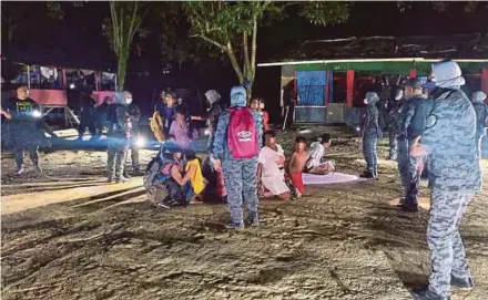  ?? PIC COURTESY OF NEGRI IMMIGRATIO­N DEPARTMENT ?? Authoritie­s standing guard over illegal immigrants detained during a raid on an illegal settlement in Nilai, yesterday.