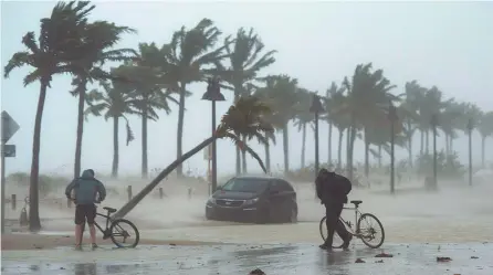  ?? AP-Yonhap ?? Two men walk their bicycles along a flooded street on the waterfront of Fort Lauderdale, Fla., as Hurricane Irma passes through, Sunday.