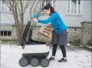  ?? RAIGO PAJULA / AGENCE FRANCE-PRESSE ?? A customer takes delivery of food from the six-wheeled robot after ordering from a restaurant in Tallinn, Estonia.