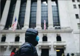  ?? Getty Images/tns ?? A woman with a facial mask passes the New York Stock Exchange (NYSE) on Feb. 3 at Wall Street in New York City.