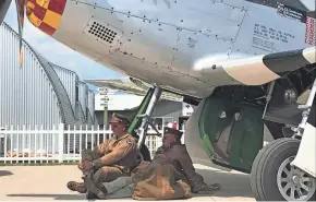  ?? MEG JONES / MILWAUKEE JOURNAL SENTINEL ?? World War II re-enactors Kevin Wisniewski of Milwaukee, left, and Steve Zahareas of Schaumburg, Illinois, find shade under a P-51 Mustang painted in the color scheme of World War II triple ace Bud Anderson, as they listen to Anderson speak during EAA AirVenture in Oshkosh.