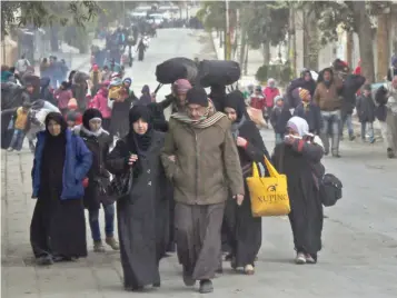  ?? — AFP ?? Residents of eastern rebel-held parts of Aleppo walk through the Kadi Askar district as they leave their homes for a safer place in a distinct rebel-controlled area on Wednesday, during a Syrian army offensive on the eastern sectors of the divided city.