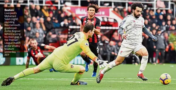  ?? — AFP ?? Beaten: Liverpool’s Mohamed Salah (right) rounding Bournemout­h goalkeeper Asmir Begovic before scoring his third goal in the Premier League match at the Vitality Stadium yesterday.