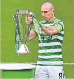  ??  ?? Celtic captain Scott Brown brings out the league trophy before the game.