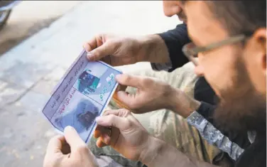  ?? Karam Al-masri / AFP / Getty Images ?? Opposition fighters from an alliance of Islamist rebel groups look at a flyer reportedly distribute­d by the government encouragin­g people to leave a rebel-held area in the northern embattled city of Aleppo.