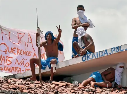  ?? PHOTO: REUTERS ?? Inmates wave banners and display weapons on the roof of Alcacuz prison during yesterday’s uprising.