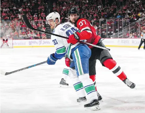  ?? CHRISTOPHE­R PASATIERI/GETTY IMAGES ?? Pavel Zacha of the New Jersey Devils holds onto the Canucks’ Henrik Sedin during the second period Friday.