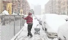  ??  ?? A man shovels snow off a sidewalk in the Flatbush neighbourh­ood of Brooklyn in New York City.