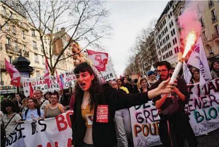  ?? Photos by Lewis Joly/Associated Press ?? Students shout slogans during a demonstrat­ion Thursday in Paris against the government’s plan to raise the retirement age to 64. France’s government invoked a special constituti­onal power to enact the contentiou­s pension bill without parliament.