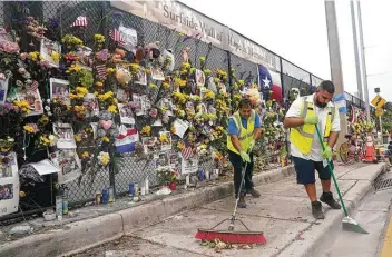  ?? Lynne Sladky / Associated Press ?? Workers sweep up dead flowers Tuesday from a makeshift memorial for victims of the collapsed Champlain Towers South condominiu­m building in Surfside, Fla. The hope of finding anyone alive is fading.