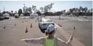  ?? JAE C. HONG/AP ?? A volunteer controls traffic at a drive-thru COVID-19 testing site in Los Angeles on Friday.